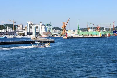 View of harbor and city during sunny day against clear sky