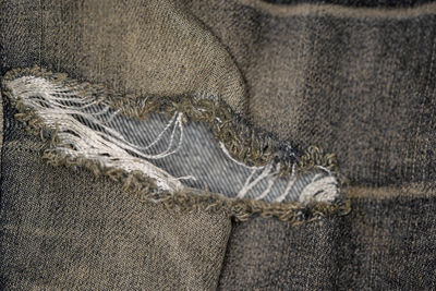 Close-up pictures of the surface of the old jeans fabric and the tear mark