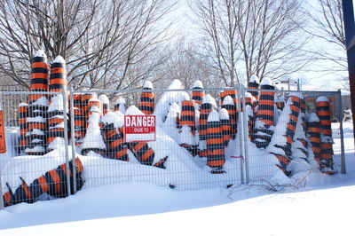 Snow covered traffic cones in fence with warning sign
