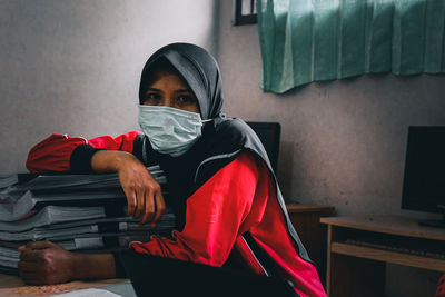 Portrait of woman wearing face mask sitting at desk