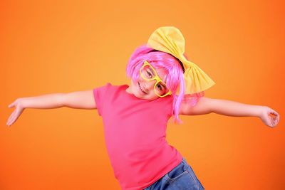 Portrait of woman with pink hair standing against orange background