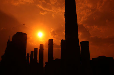 Low angle view of wooden post against orange sky