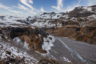 Beautiful view of stream amidst snow covered mountains in valley against sky