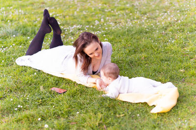 Cheerful mother lying on front with baby at park