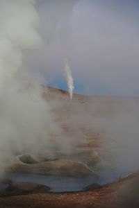 Smoke emitting from volcanic landscape against sky