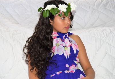 Girl wearing flowers while lying on bed at home