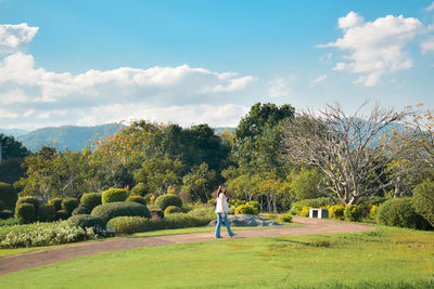 Rear view of woman walking on field against sky