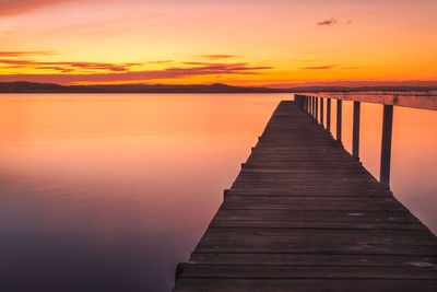 Pier over sea against orange sky