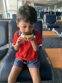 Cute boy eating food at airport terminal