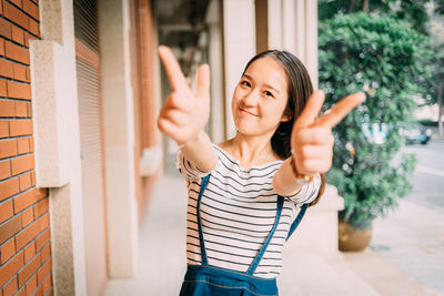 Portrait of smiling young woman gesturing in corridor