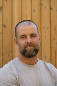 Portrait of the handsome man with beard standing against wooden background