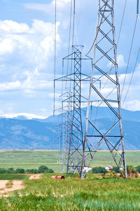 Electricity pylon on field against sky