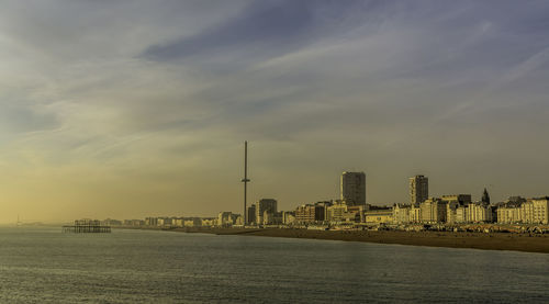 City at waterfront against cloudy sky