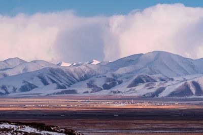 Scenic view of snowcapped mountains against cloudy sky