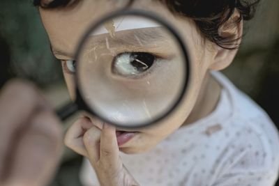 Close-up portrait of boy seen through magnifying glass