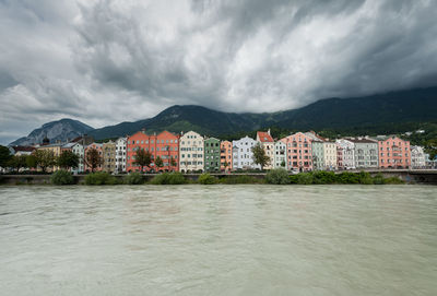 Buildings by houses against sky in city