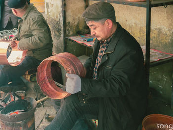 Men looking at man holding camera while standing outdoors