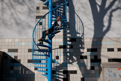 Low angle view of woman sitting on spiral staircase