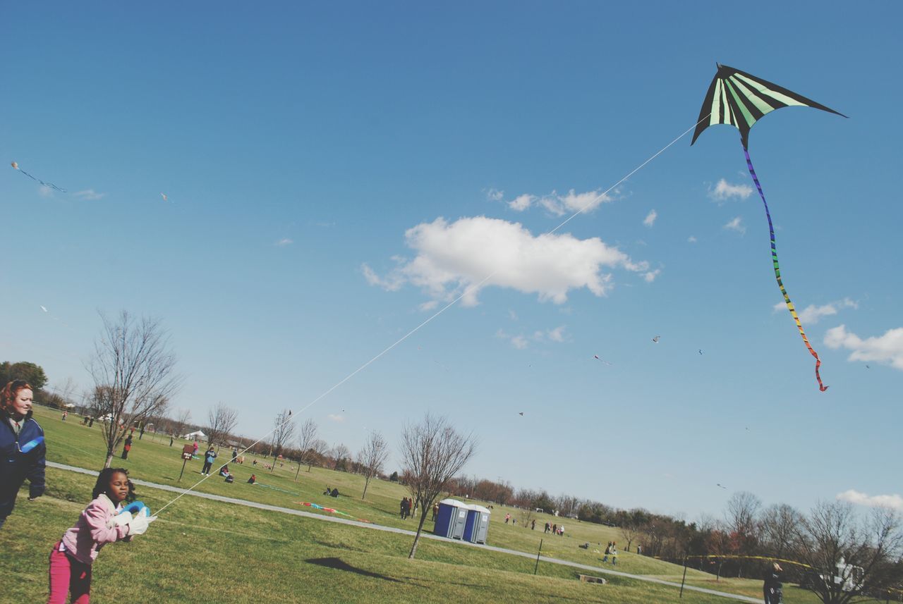 flying, sky, leisure activity, grass, field, tree, lifestyles, mid-air, landscape, blue, men, day, nature, cloud - sky, transportation, sport, person, clear sky