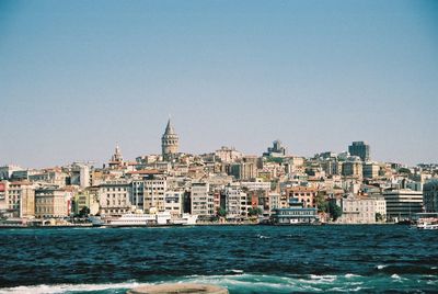 Cityscape by sea against sky