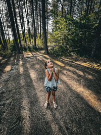 Rear view of girl walking on field in forest