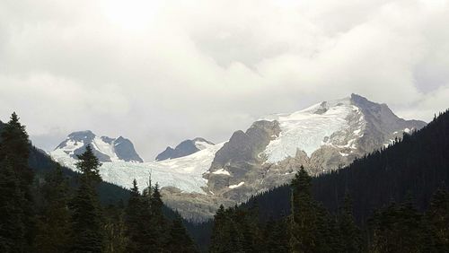 Snow covered mountains against cloudy sky