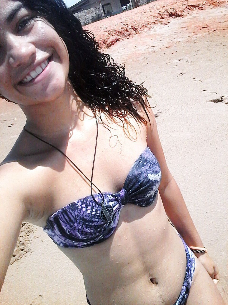 CLOSE-UP PORTRAIT OF HAPPY WOMAN AGAINST BEACH