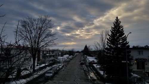 Street amidst buildings against sky during sunset