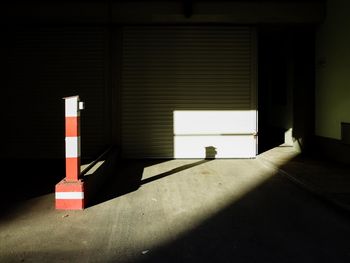 Stripped pole with shadow on footpath