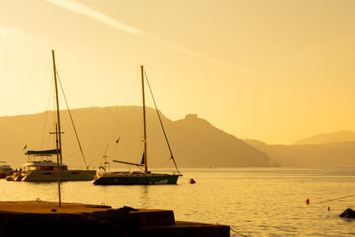 Sailboats sailing on sea against sky during sunset