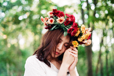 Portrait of woman holding red flowering plant