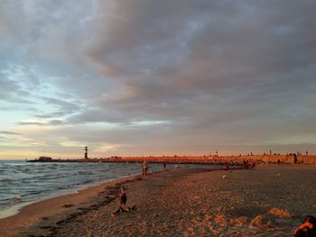 People on beach against sky during sunset