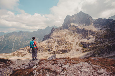 Rear view of man climbing on mountain against sky