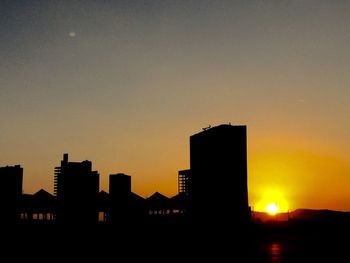 Silhouette buildings against sky at sunset