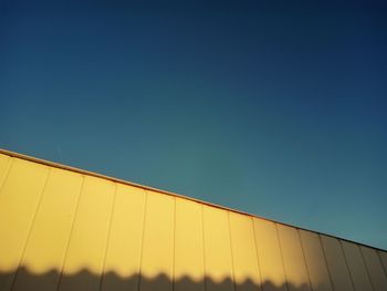Low angle view of yellow structure against clear blue sky