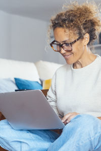 Portrait of young woman using mobile phone while sitting at home