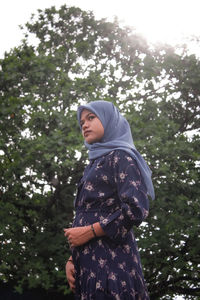 Low angle view of woman standing against trees