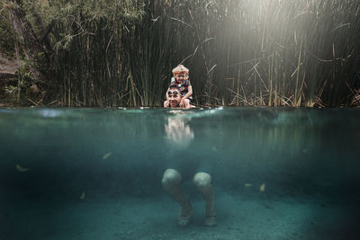 Father carrying son on shoulders while swimming in lake