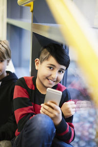 Portrait of smiling boy holding smart phone in middle school