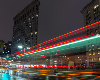 Light trails on road against buildings at night