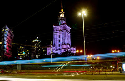 Light trail on road against buildings at night