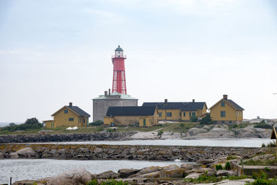 Lighthouse by building against sky