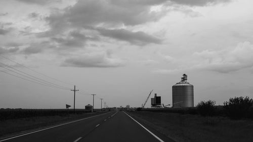 Road leading towards tower against sky