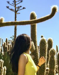 Rear view of woman on cactus against sky