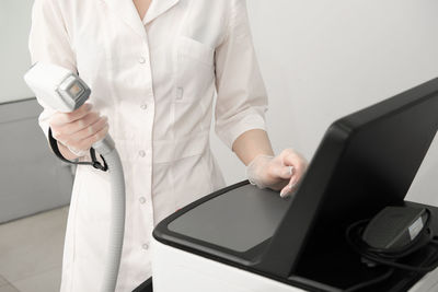 Woman in white uniform adjusting laser epilation machine in beauty salon. body care and cosmetology 