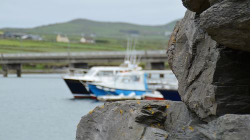 Boat moored on rock by sea against sky