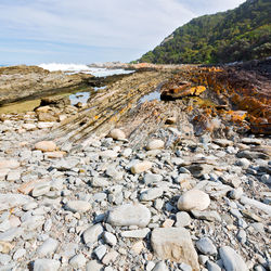 Surface level of stones on beach against sky