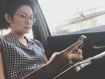 Low angle view of mature woman using mobile phone while sitting in car