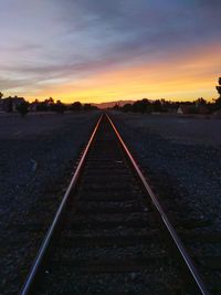 Railroad tracks against sky during sunset