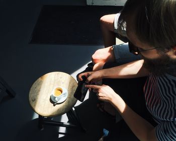 High angle view of man photographing coffee on table with mobile phone